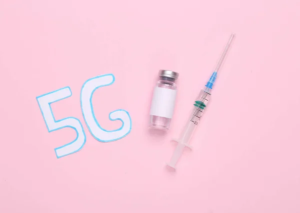 conspiracy theory. 5G word and vaccine bottle with syringe on pink background
