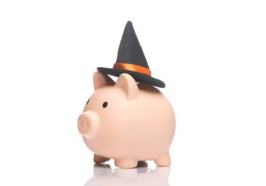 Cadılar Bayramı konsepti Cadı şapkalı domuz kumbarası beyaz arka planda yansımalı.