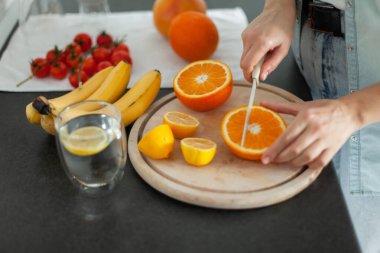 Sağlıklı gıda konsepti. Mutfak tahtasında meyve kesen bir kadın.