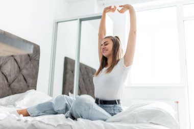 Genç bayan uyuduktan sonra kollarını parlak bir odada gerer.