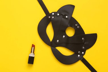 Aşk, romantik, seksi konsept. Deri bdsm seksi kedi maskesi, sarı arka planda ruj izi var..