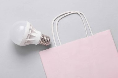 Gri arka planda alışveriş torbası olan ampul