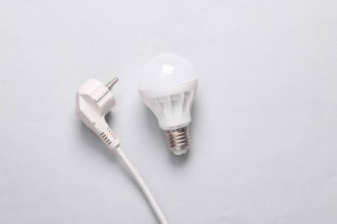 Gri arka planda elektrik prizi olan ampul. Üst görünüm