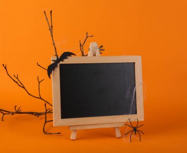 Turuncu arka planda boş tebeşir tahtası olan Cadılar Bayramı dekoru. Cadılar bayramın kutlu olsun, şeker mi şaka mı?