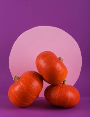 En az Cadılar Bayramı hala hayattadır. Mor arka planda pembe çemberli üç balkabağı. Yeni bir fikir. Yaratıcı yerleşim