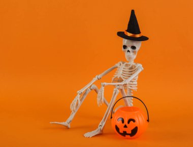 Şeker mi şaka mı? Anneciğim. Cadı şapkalı iskelet ve turuncu arka planda Jack Lantern şeker kovası. Cadılar Bayramı 'nda hayat çok azdı. yaratıcı yerleşim