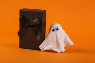 Cadılar Bayramı hala hayat. Turuncu arka planda hediye kutusu olan hayalet.