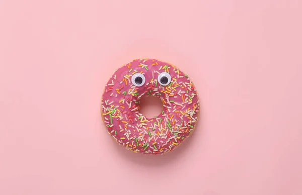Minimal food concept. Donut with eyes on a pink background