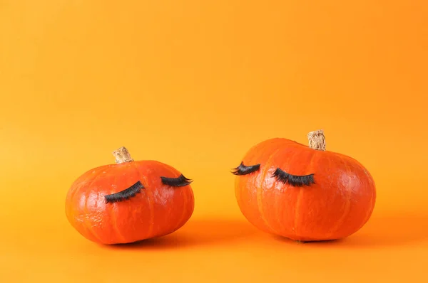 stock image Minimal halloween still life. Two Cute pumpkins with false eyelashes on orange background. Creative idea, beauty industry