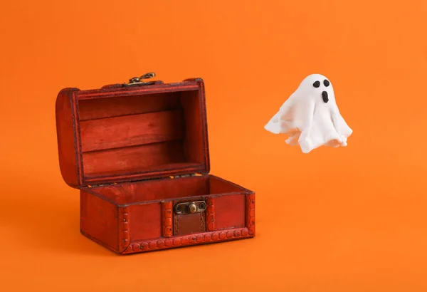 Ghost guarding a pirate chest on an orange background. Halloween concept
