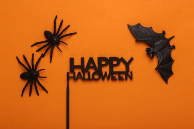 Yarasalı plastik örümcekler ve turuncu arka planda mutlu cadılar bayramı. Cadılar Bayramı dekoru. Üst görünüm