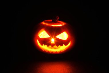 Korkunç gülümseyen cadılar bayramı balkabağı kabağı kafası ve siyah arka planda yanan bir mum