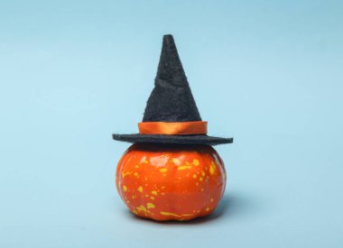 Korkunç yüzlü plastik balkabağı, mavi arka planda cadı şapkası ve süpürge. Cadılar Bayramı hayat dolu