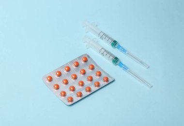 Tıbbî hayat. Mavi arka planda hap dolu bir şırınga.