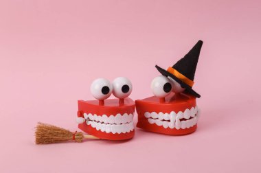 Two Funny lhalloween clockwork jumping teeth toy on pink background.
