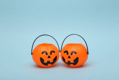 Halloween pumpkins orange candy buckets with face on blue background. Trick or Treat