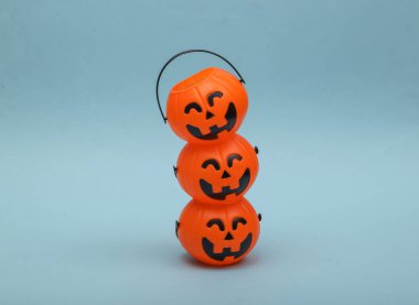 Stack of halloween pumpkins orange candy buckets with face on blue background. Trick or Treat