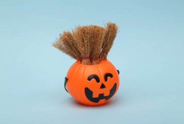 Halloween pumpkins orange candy bucket with brooms on blue background. Trick or Treat