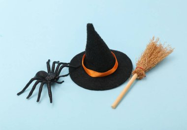Halloween decor. Witch hat with broom and spider on blue background