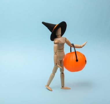 Halloween puppet in a witch hat holds a Halloween bucket on a blue background. Trick or Treat.