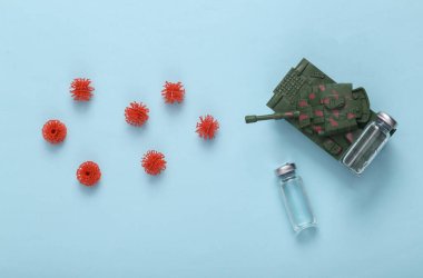 Immune system, antivirus and pathogen, vaccination. Plastic toy tank with vaccine bottle fights with virus molecules on blue background