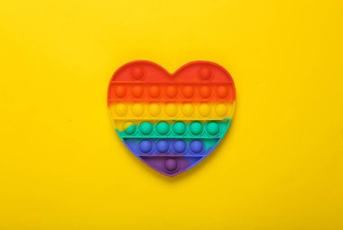 Pop it sensory rainbow antistress heart shaped toy on yellow background