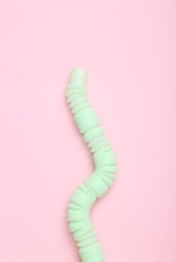 Antistretch pop tube toy on pink pastel background. Top view