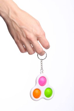 Hand holding simple dimple antistress toy on a white background