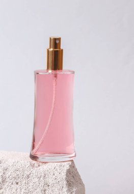 Natural cosmetic. Beauty products. Perfume bottle on stone podium, gray background. Product photo. Abstract natural composition