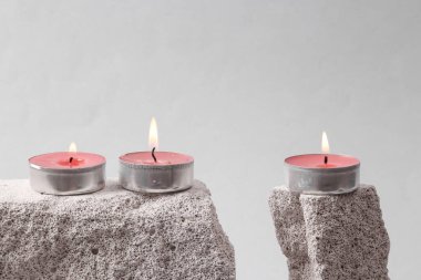 Flaming scented tea candles on stone. Gray background. Minimal concept.