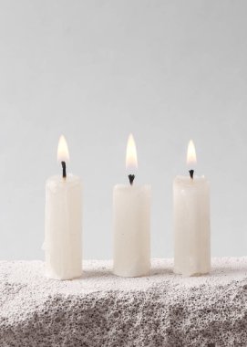 Flaming candles on stone. Gray background. Minimal concept.