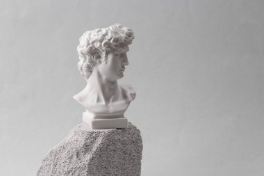 Minimalistic scene of antique bust of David on stones
