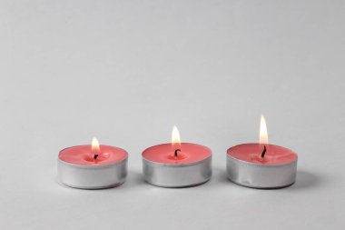 Flaming scented tea candles on gray background