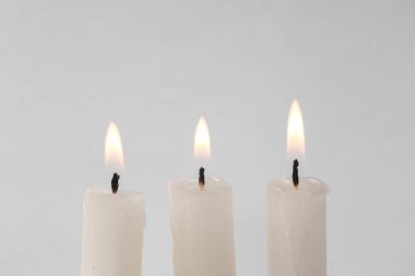 Flaming wax candles on a gray background