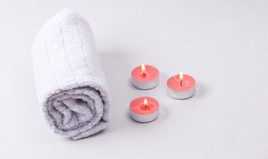 Aromatherapy, spa salon. Scented candles with towel on gray background
