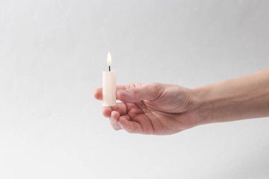 Female puka holding a flaming candle on a gray background