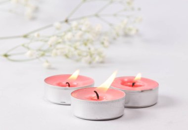 Flaming scented tea candles on gray background.