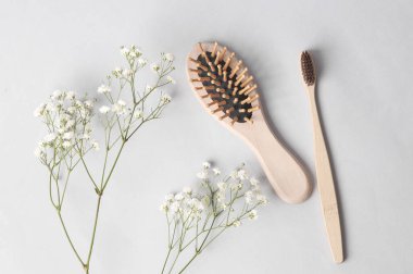 Eco, natural, plastic free. Bamboo toothbrush and wooden hair brush with sprig on gray background