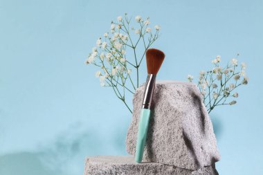 Beauty products. Makeup brush on stones, blue background. Product photo. Abstract natural composition