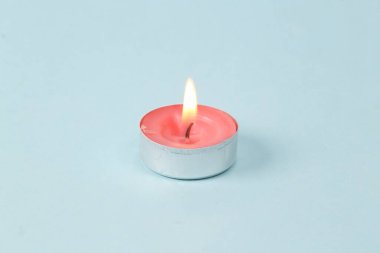 Flaming scented tea candle on blue background