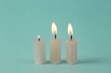 Flaming wax candles on a turquoise background