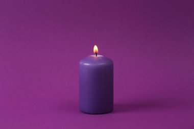 Flaming purple aroma candle on a purple background