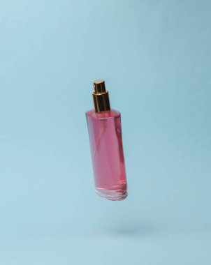 Perfume bottle flying in antigravity on blue background with shadow. Levitation object in the air. Beauty and fashion concept. creative minimalist layout