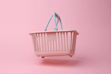 Supermarket basket flying in antigravity on pink background with shadow. Levitation object in the air. Shopping, sale concept. Creative minimalist layout