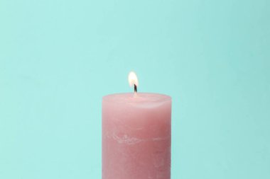 Pink flaming candle on mint green background. Pastel color trend