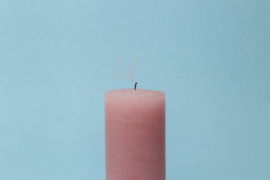 Pink smoking candle on blue background. Pastel color trend