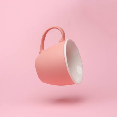 Pink ceramic cup flying in antigravity on pink background with shadow. Levitation object in the air. Creative minimal layout