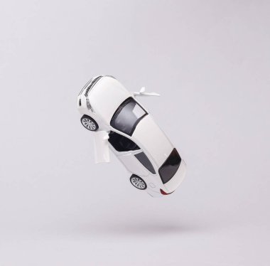 Miniature car model flying in antigravity on gray background with shadow. Levitation object in the air. Creative minimal layout