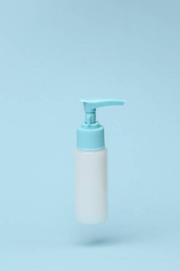 Cream dispenser bottle flying in antigravity on blue background with shadow. Levitation object in the air. Beauty and fashion concept. Creative minimal layout