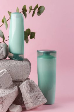 Shampoo bottles on stone with eucalyptus branch. Natural cosmetics, beauty concept. Hair care. Modern still life, product photo. Aesthetic minimalist composition.